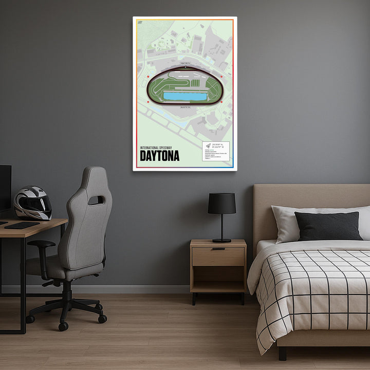 Room interior with a bed, desk, chair, and framed canvas of Daytona International Speedway on the wall.
