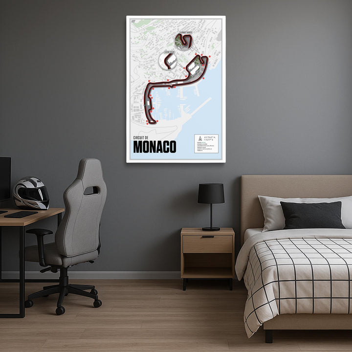 Room interior with a framed map of Monaco on the wall, desk, chair, and bed.